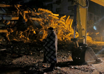 A man stands in front of a collapsed building after an earthquake in Osmaniye, Turkey February 6, 2023.