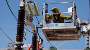 A technician wearing a protective suit works on an electrical substation.