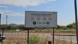 A sign post, security vehicle and fence leading into Bakubung mine