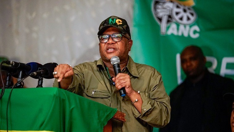 Mbalula gestures while holding a mic