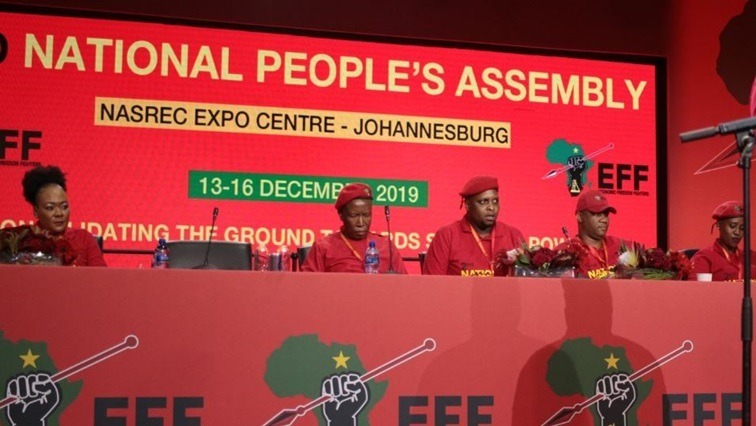 EFF leaders on the podium in front of a party banner