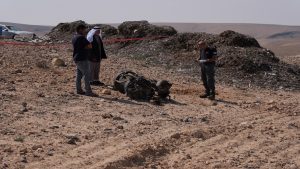 A police officer and residents inspect the remains of a rocket booster that, according to Israeli authorities critically injured a 7-year-old girl, after Iran launched drones